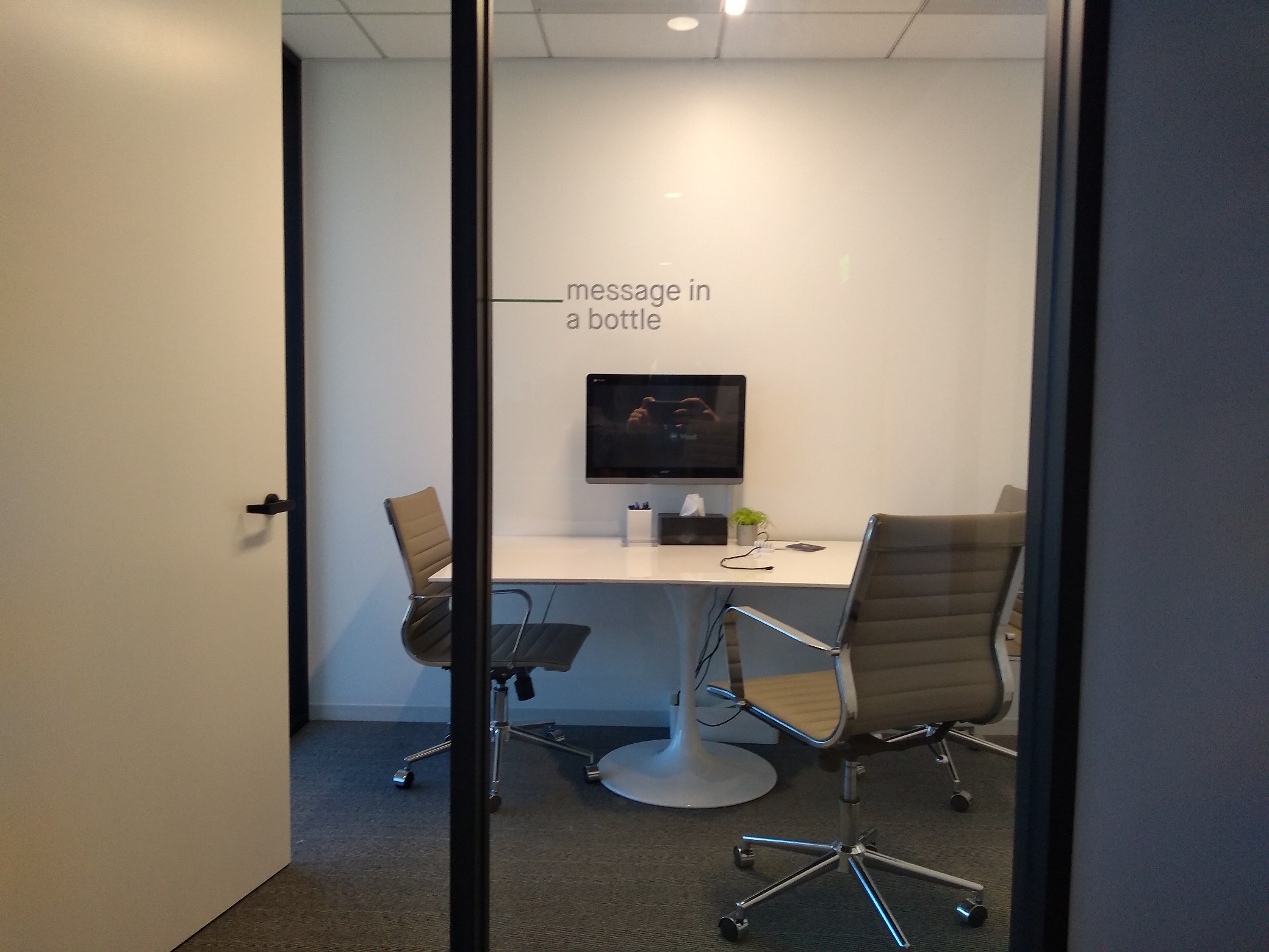 Picture of a meeting room, with a sign next to the door that says “message in a bottle”