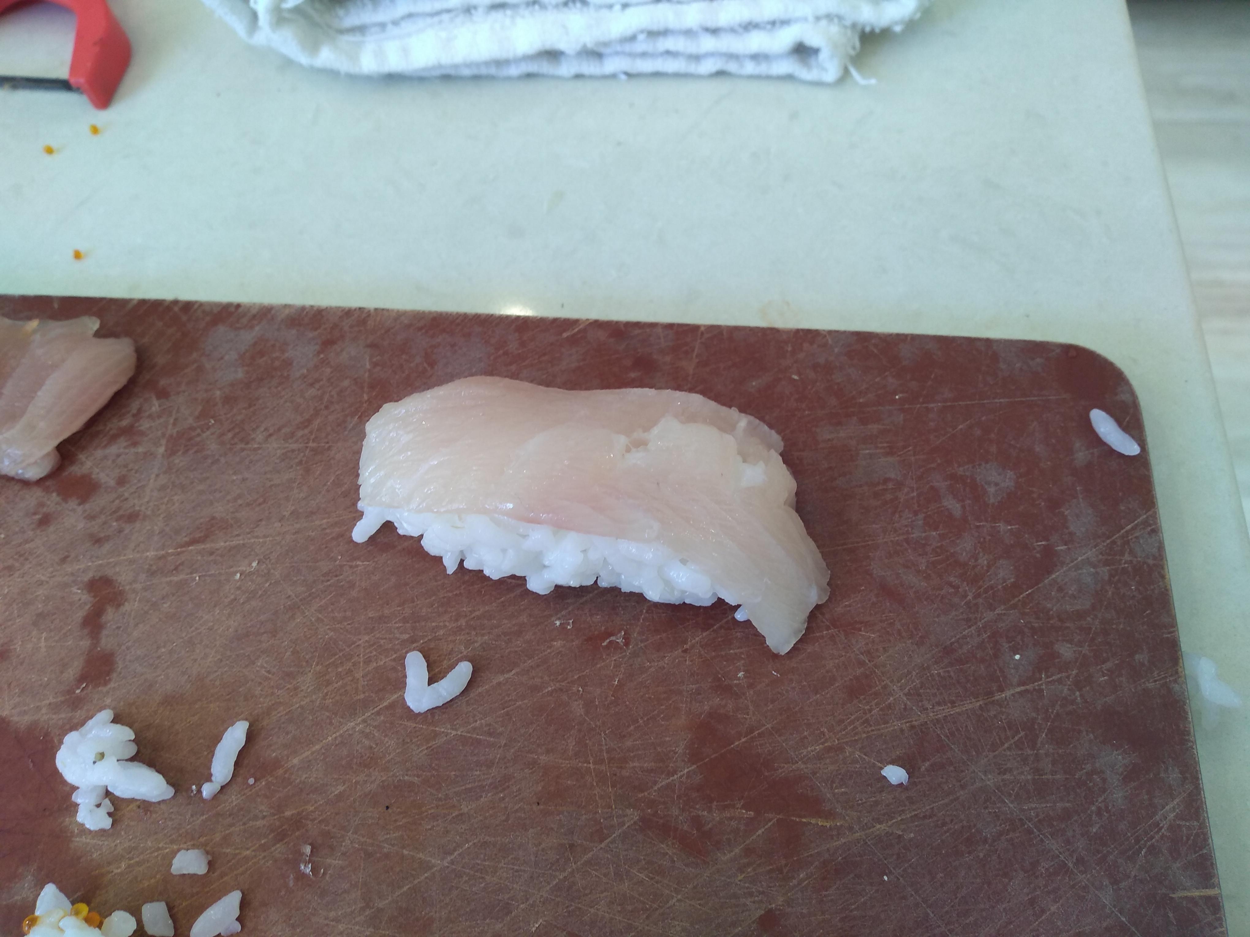 A slice of rice on a lump of fish.