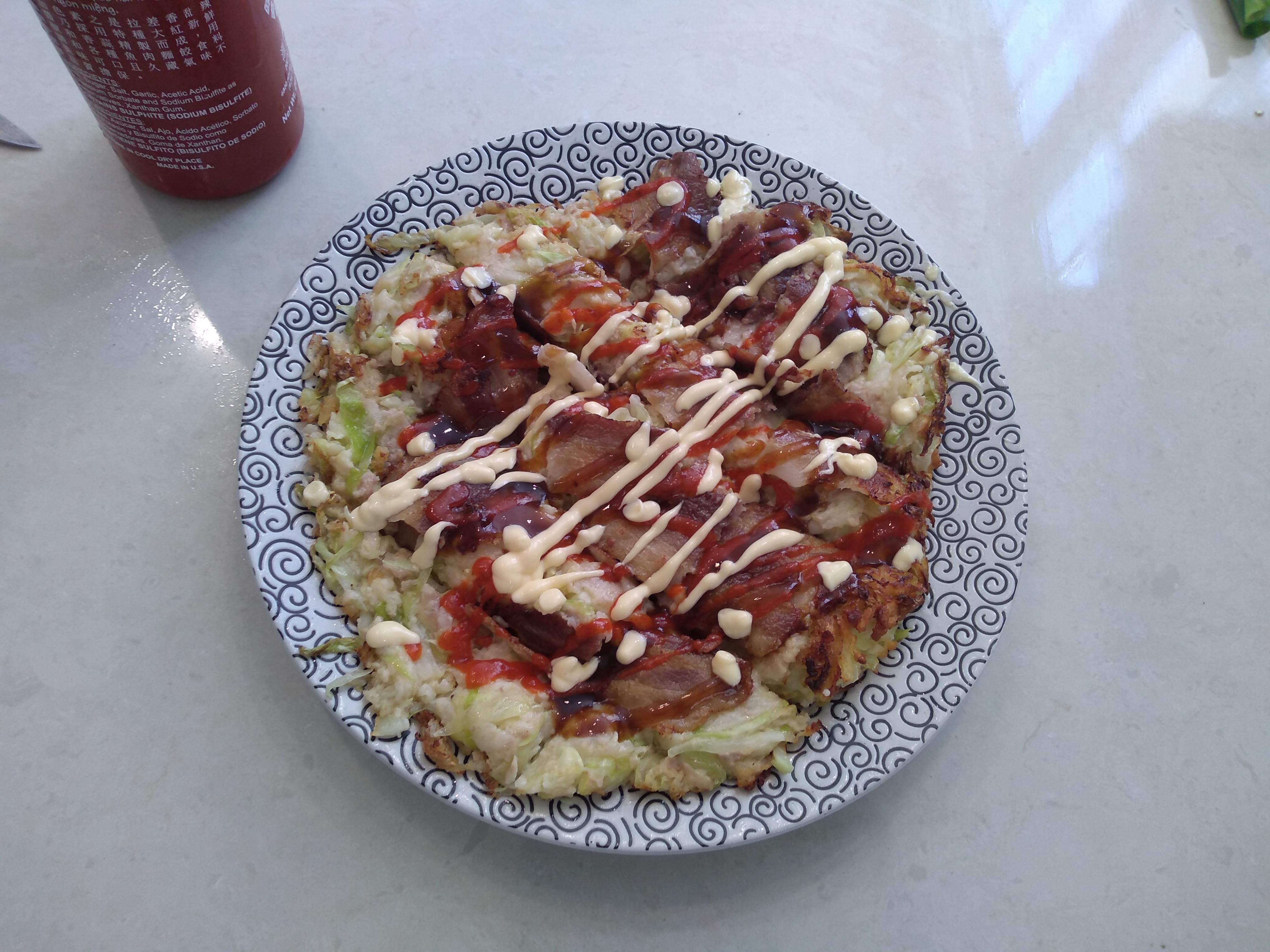 A plate holding a multicolored flat blob, with sauce squiggled over it.