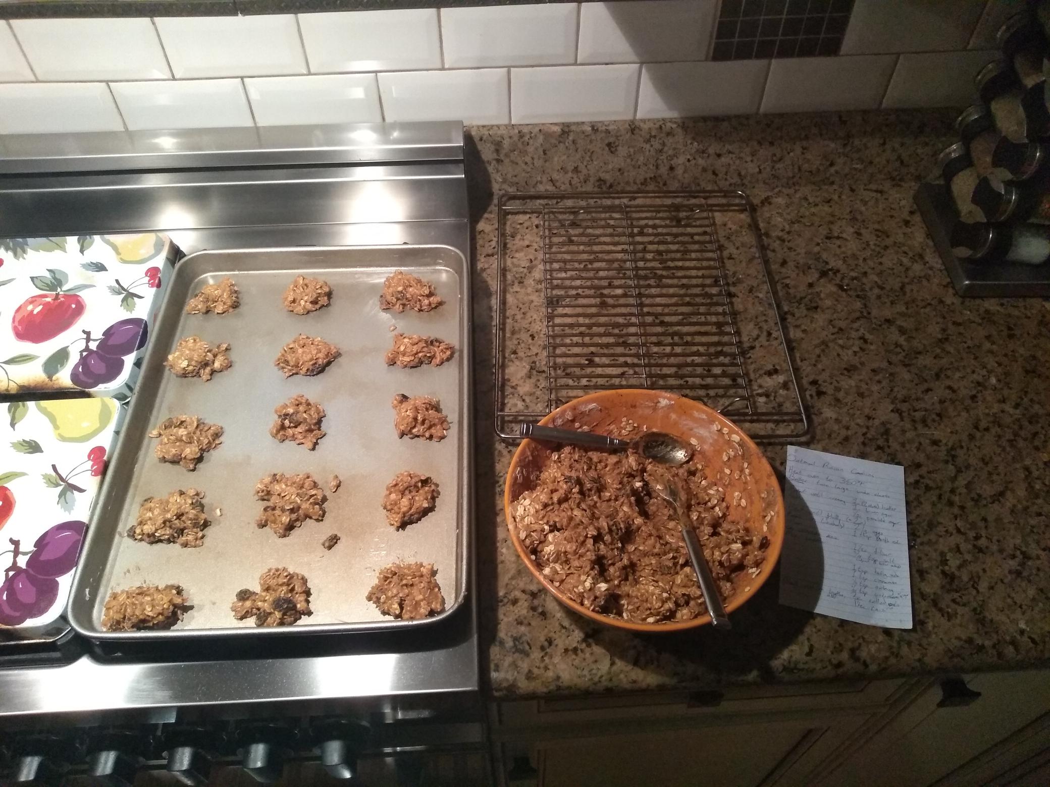 A bowl of raw cookie dough, and a baking tray splotched with cookies.