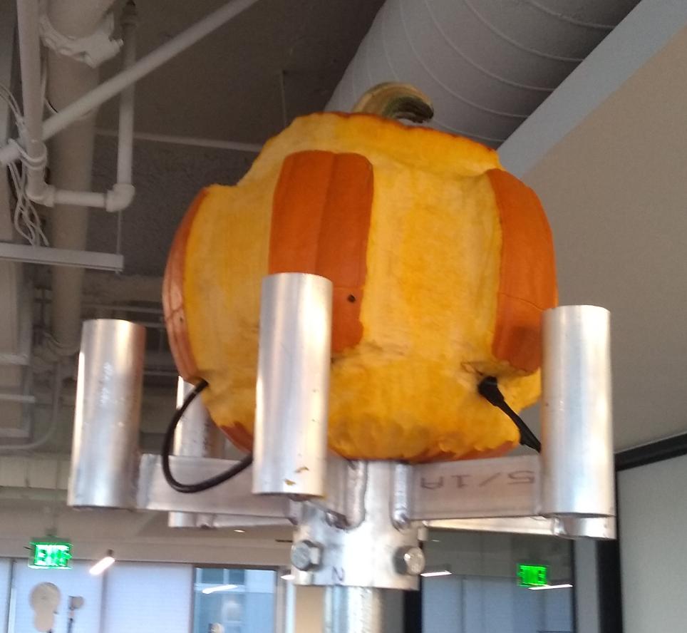 A pumpkin with ethernet cables sticking out, mounted on a metal pole.