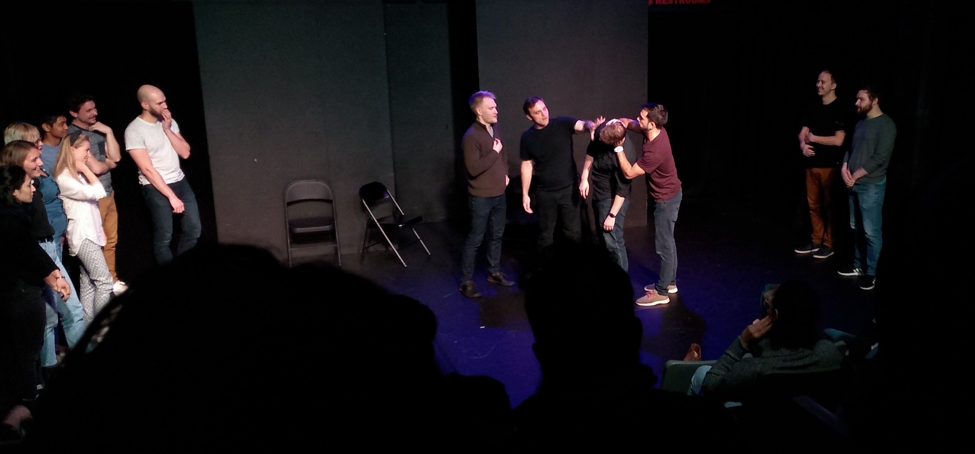 Three people standing around and looking at the fourth one’s head.