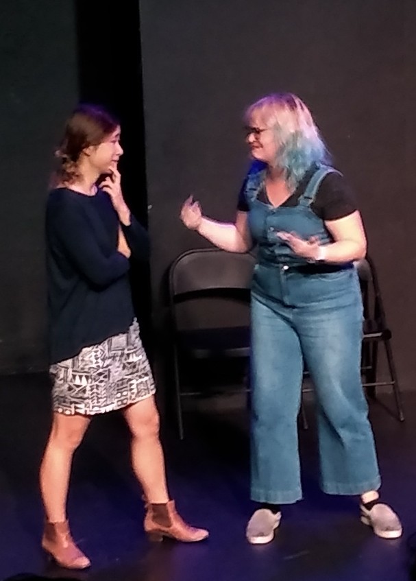 Two women facing each other, one looking very distraught and the other concerned.