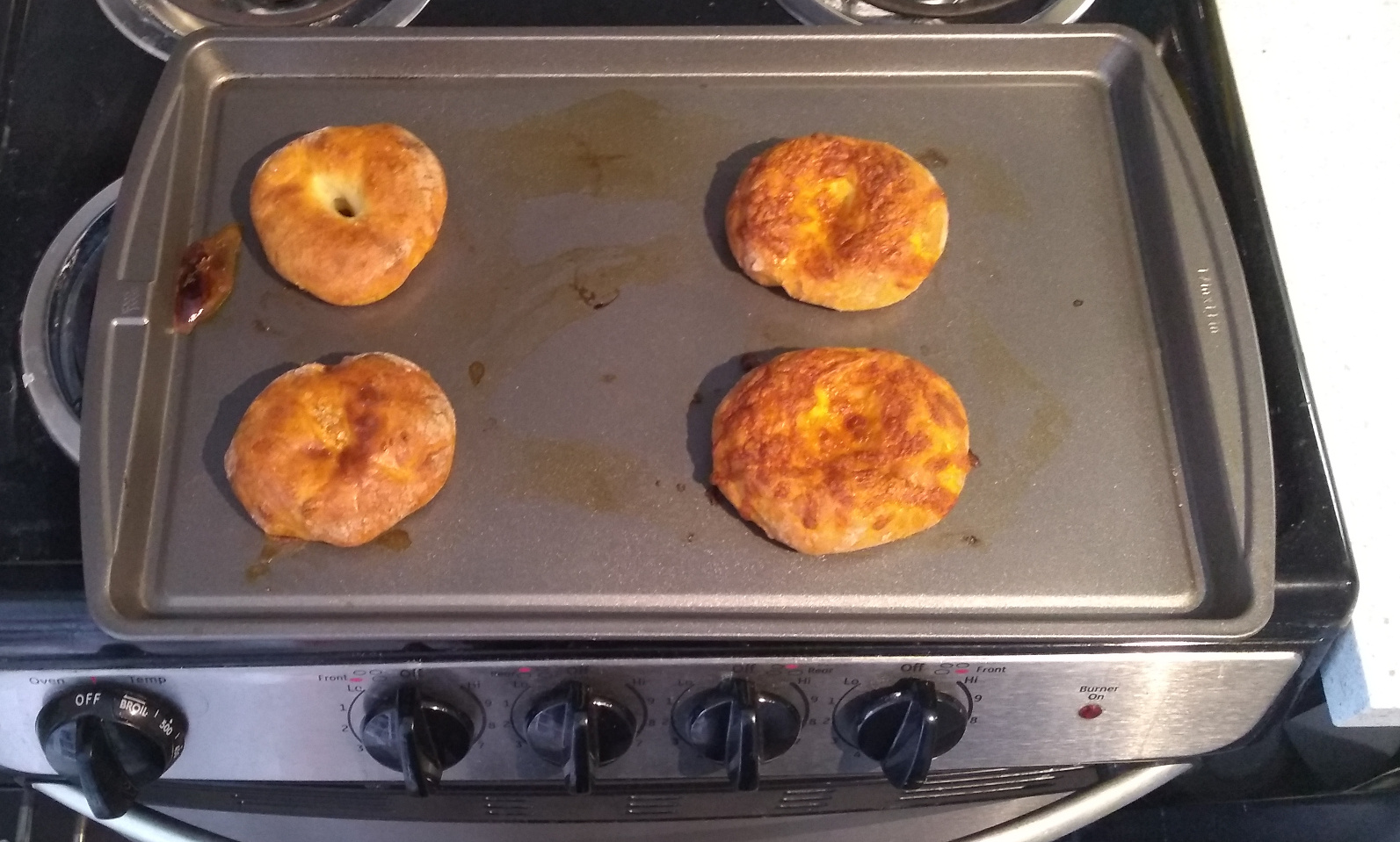 A baking tray with four round doughy shapes on it, looking nicely browned.