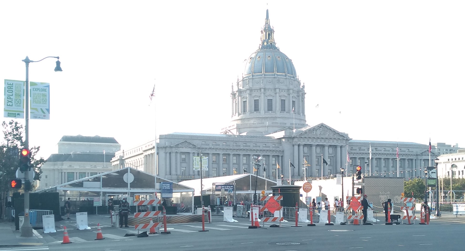 Several large tents in the middle of the street with Road Closed signs in front, and City Hall in the background.