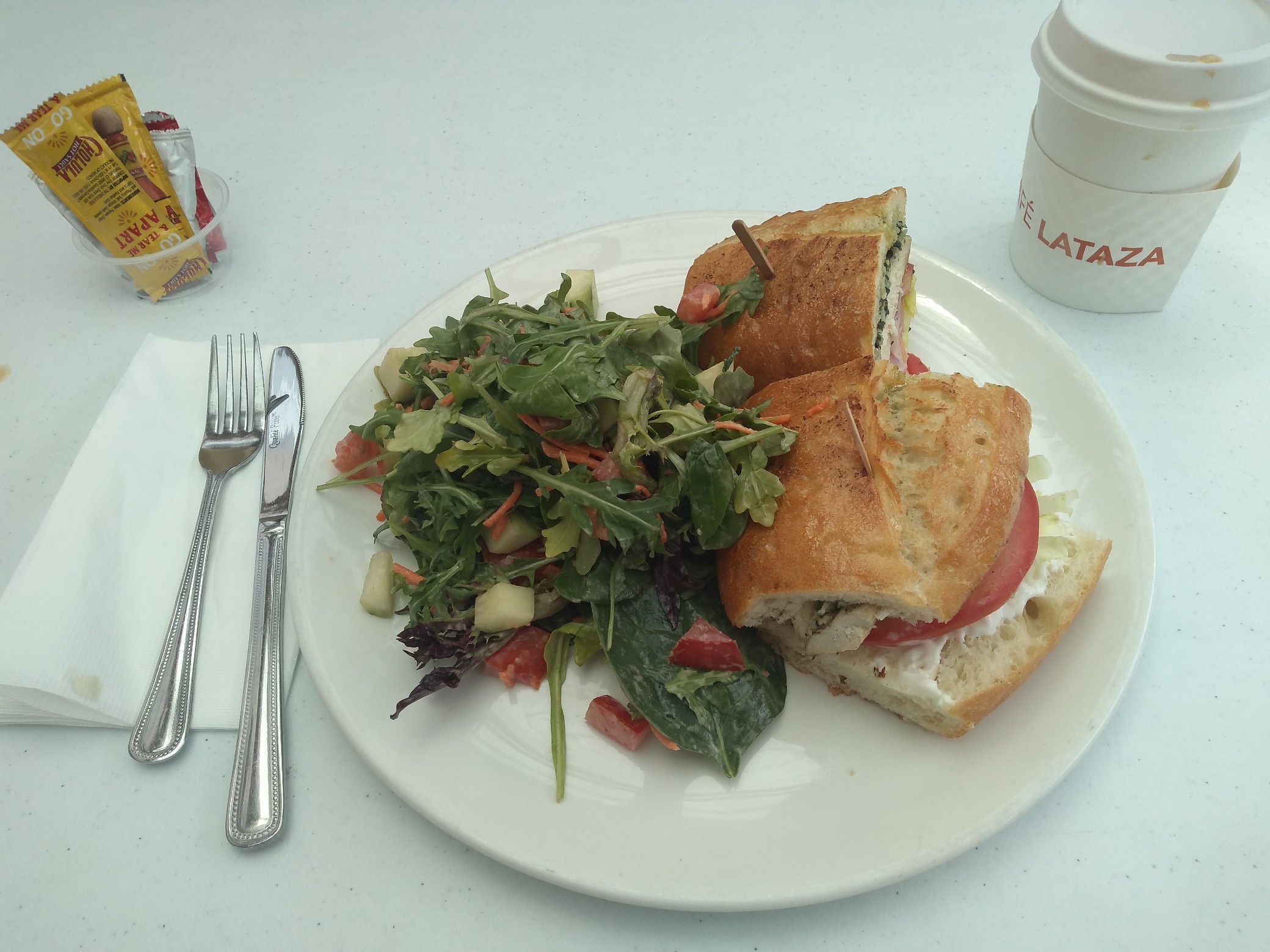 A plate with a very fancy salad and sandwich.