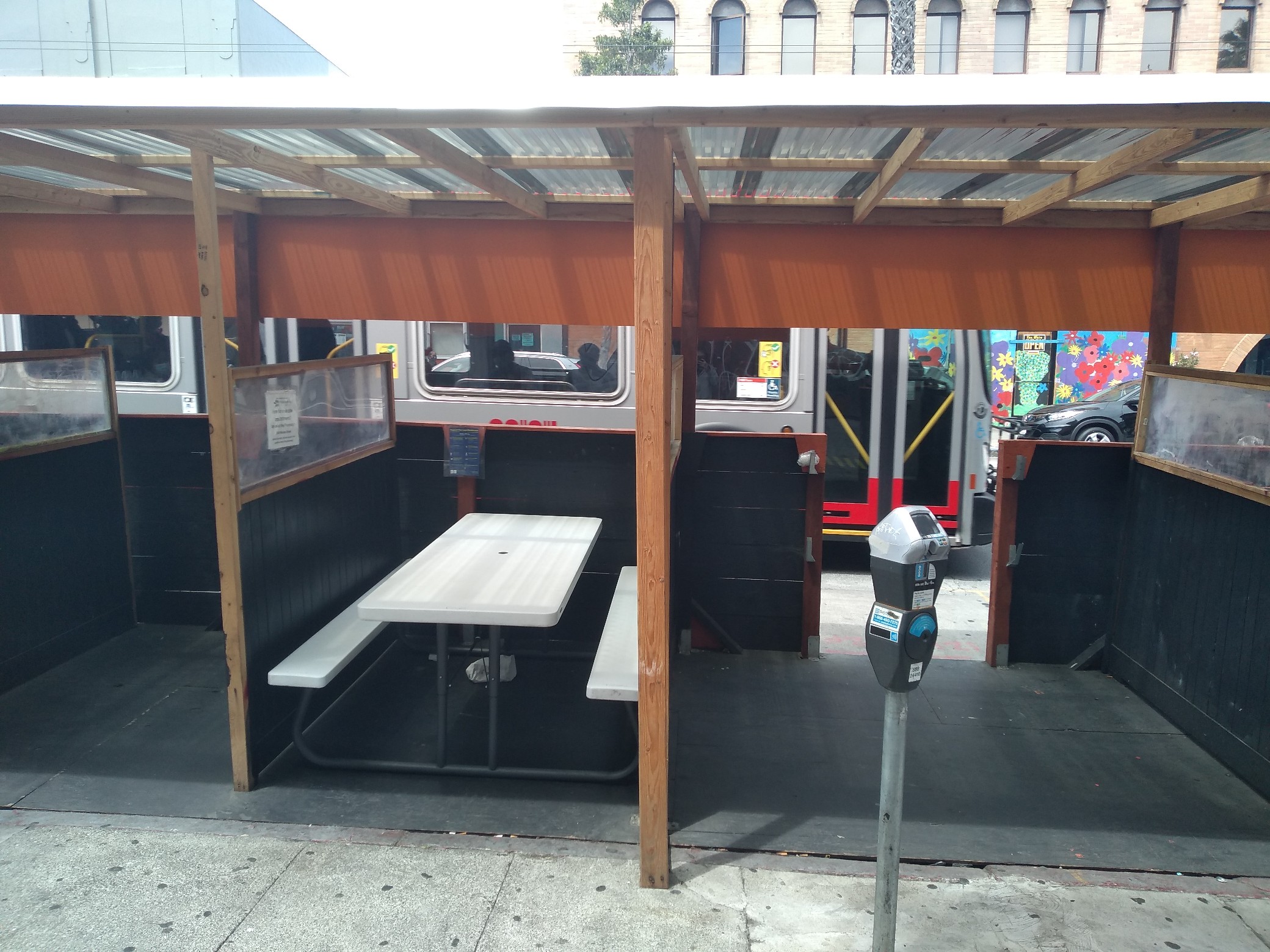A rough-hewn wood shelter with folding tables between partitions.