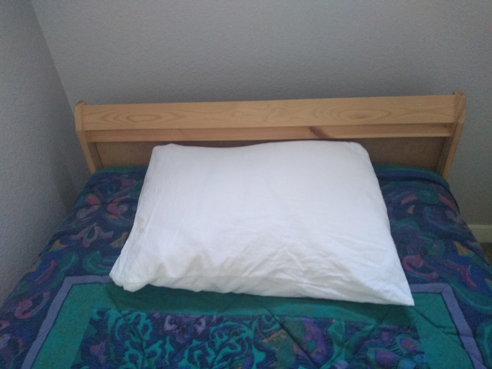 Neatly made bed, with a pillow now protected from the precipice.
