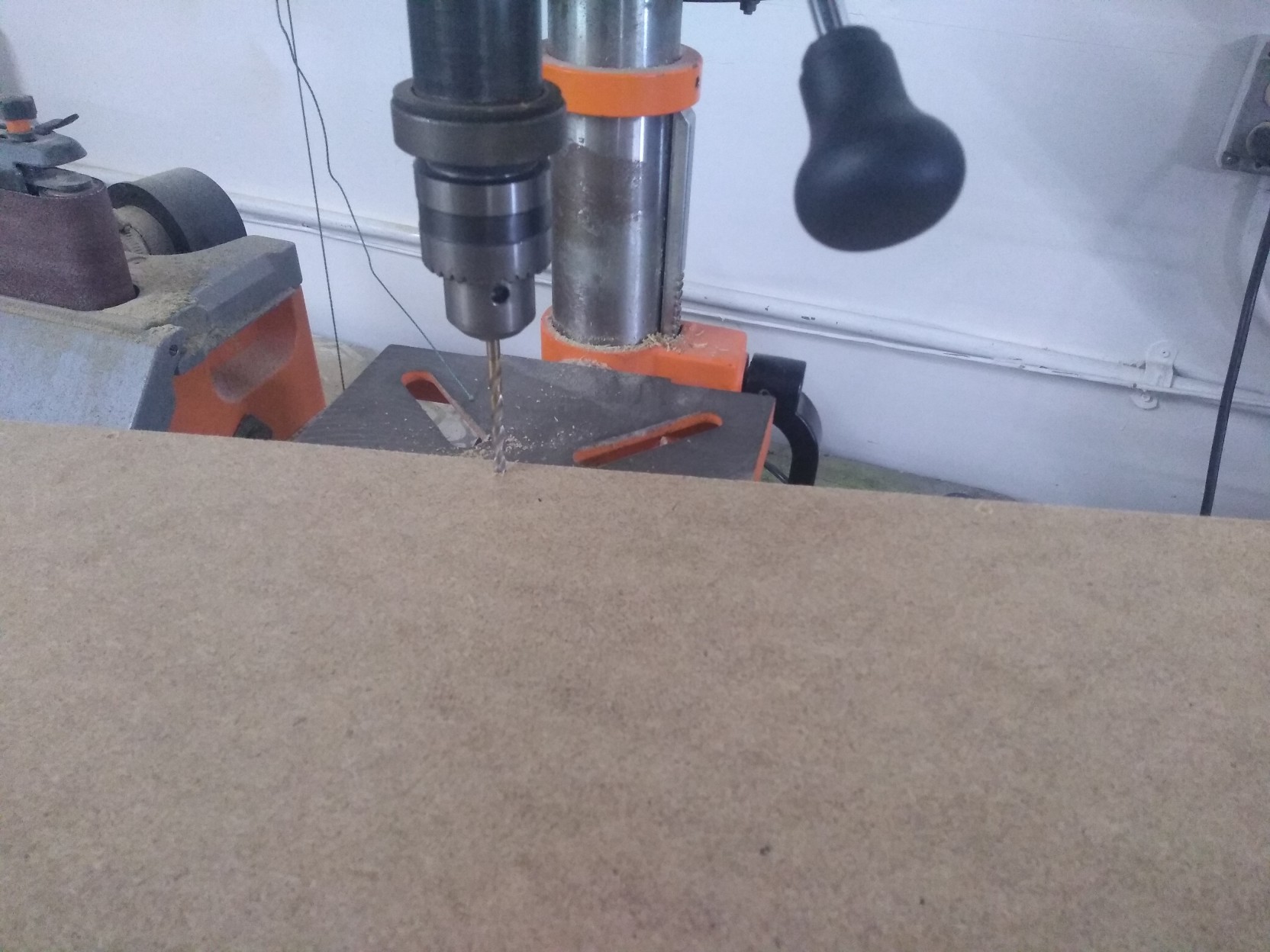 Drill press drilling near one edge of the board.