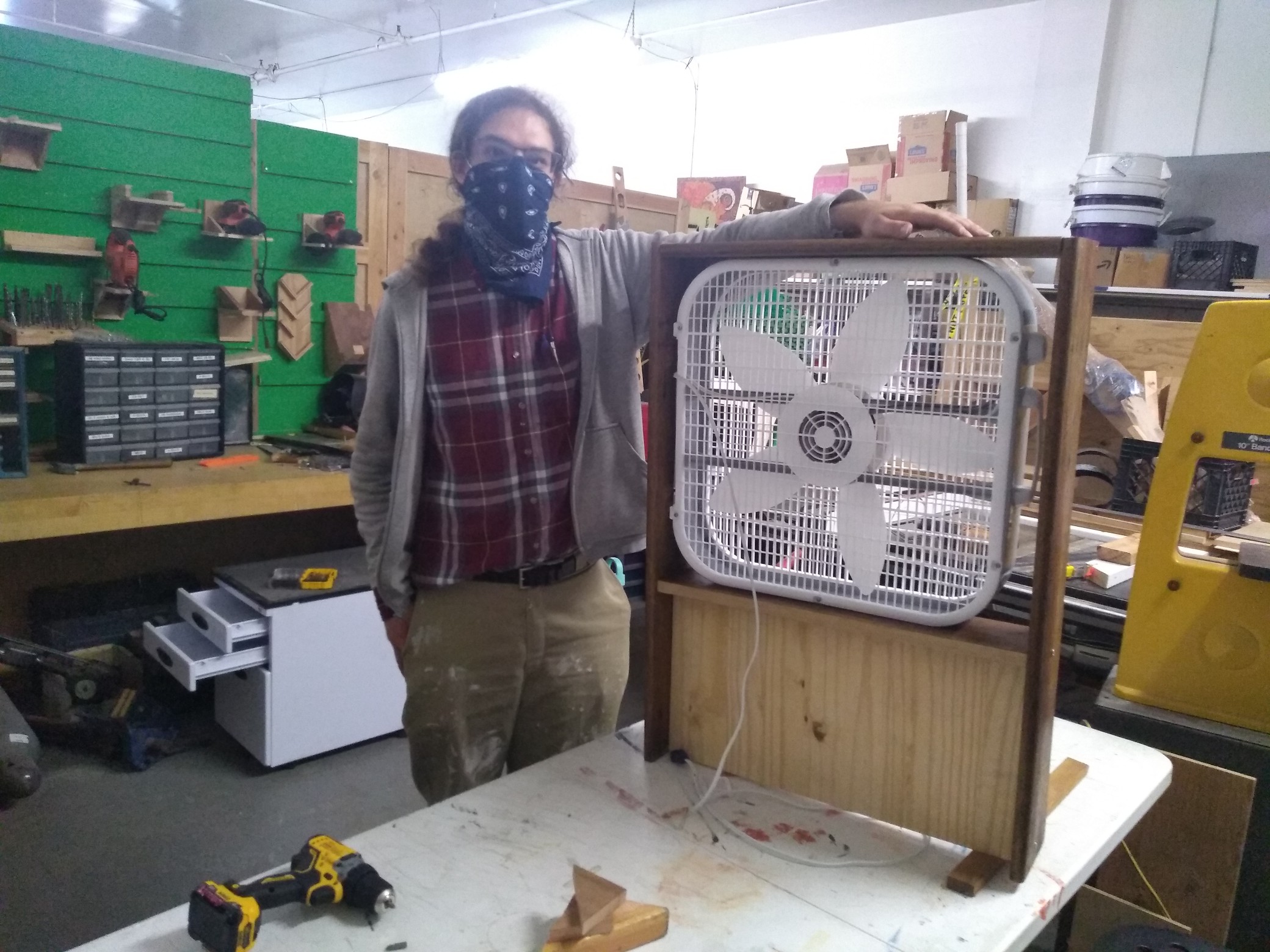 In the woodshop: Wolf stands next to a box fan in a wooden frame.